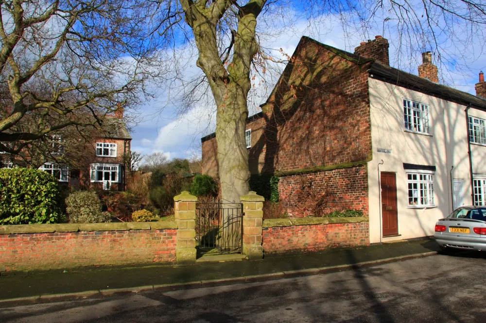A brick house and cottage behind a low wall on Water End, Brompton